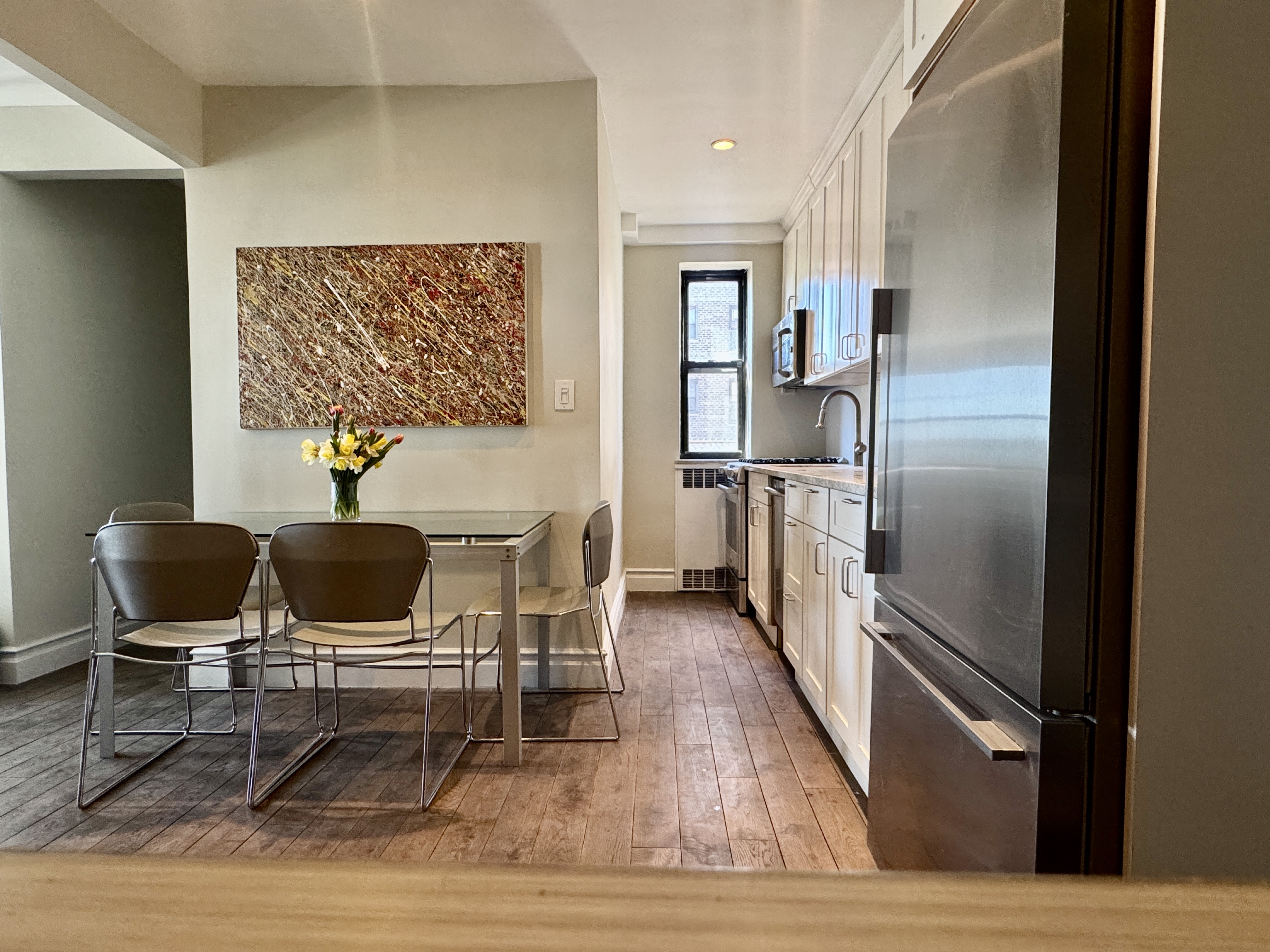 90 Park Terrace East, Unit 3B Manhattan, NY 10034 - Photo 5 of 13 a kitchen with granite countertop a refrigerator cabinets and wooden floor