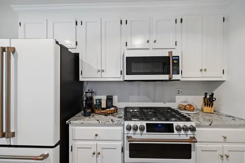 a kitchen with stainless steel appliances a stove a sink cabinets and a wooden floor