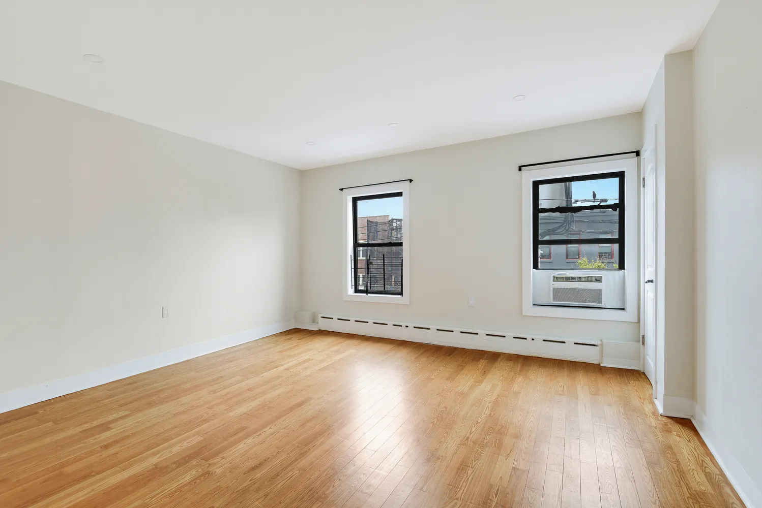 an empty room with wooden floor and windows