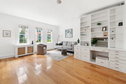 a large white room with stainless steel appliances kitchen island granite countertop a stove a sink a refrigerator and white cabinets with wooden floor