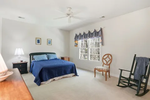 a bedroom with a bed a mirror on dresser and a large window