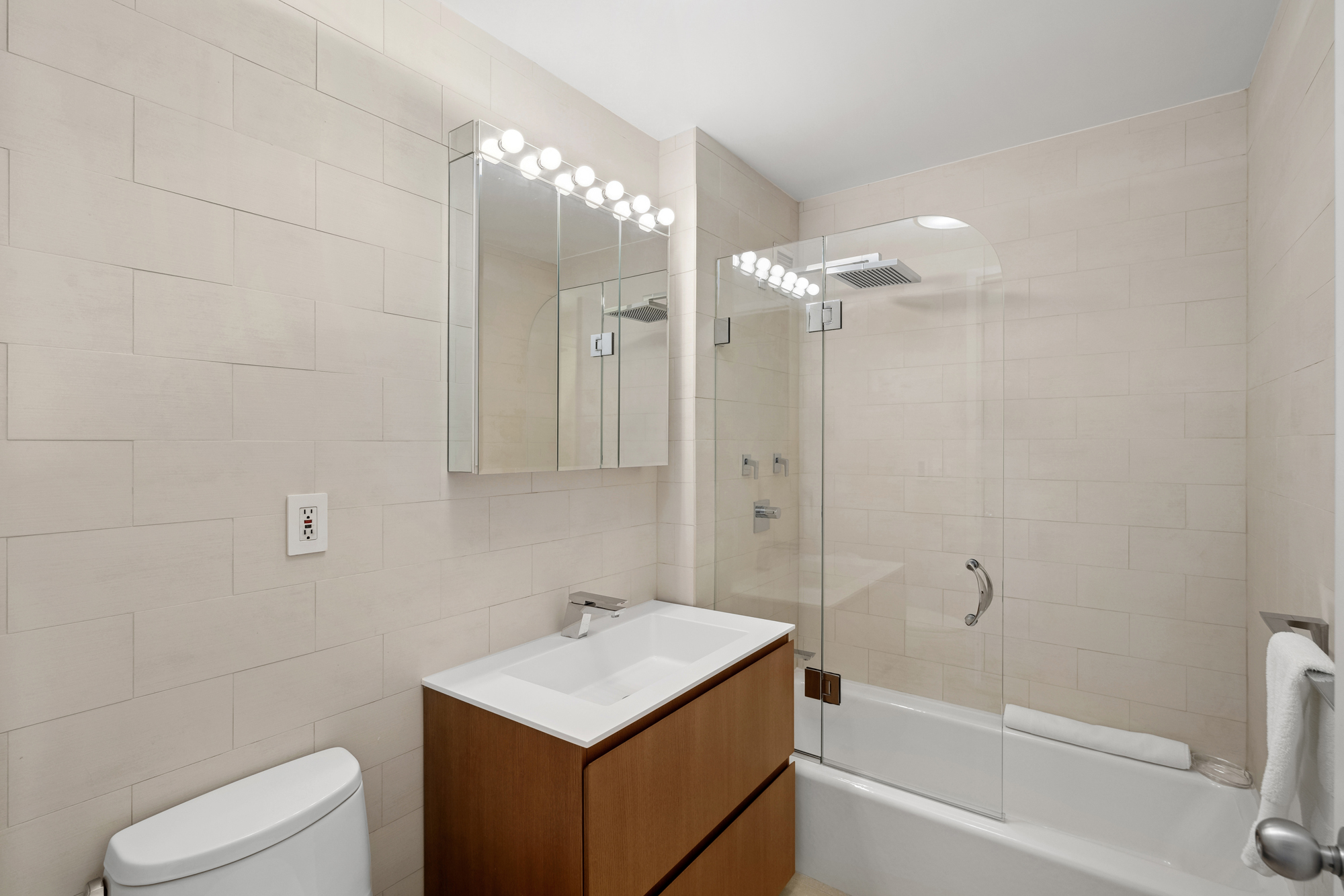 99 Jane Street, Unit 4H Manhattan, NY 10014 - Photo 11 of 22 a bathroom with a sink a toilet a mirror and shower