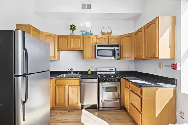 a kitchen with stainless steel appliances granite countertop a refrigerator a stove and a sink