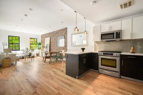 a kitchen with stainless steel appliances kitchen island granite countertop a stove top oven a sink dishwasher a dining table and chairs with wooden floor