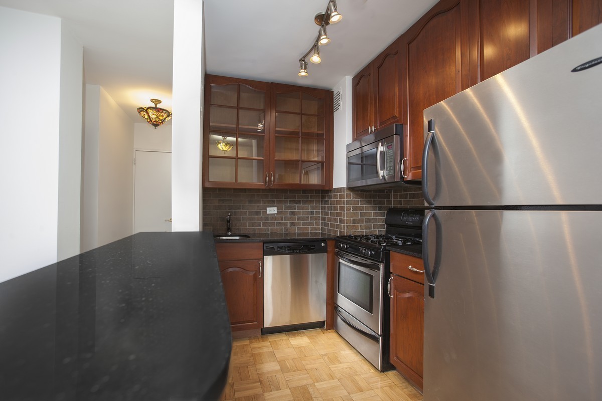 320 East 54th Street, Unit 8B Manhattan, NY 10022 - Photo 3 of 6 a kitchen with stainless steel appliances granite countertop a refrigerator a sink and a stove