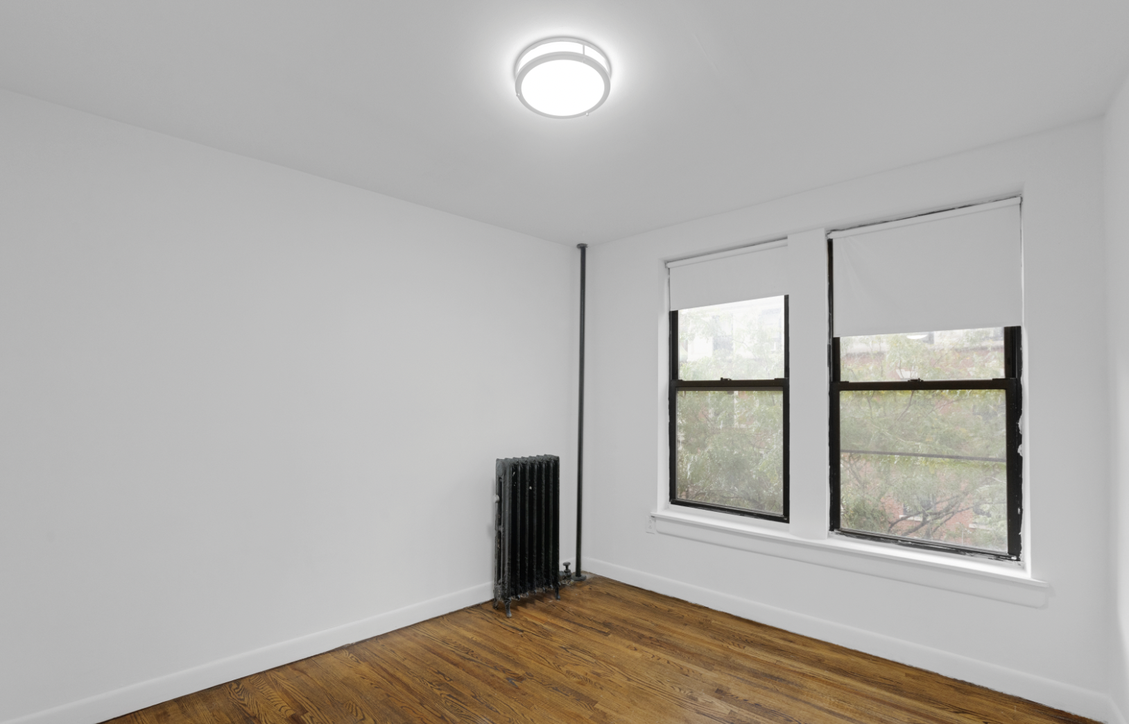 24 East 97th Street, Unit 21 Manhattan, NY 10128 - Photo 2 of 5 a view of an empty room with window and wooden floor