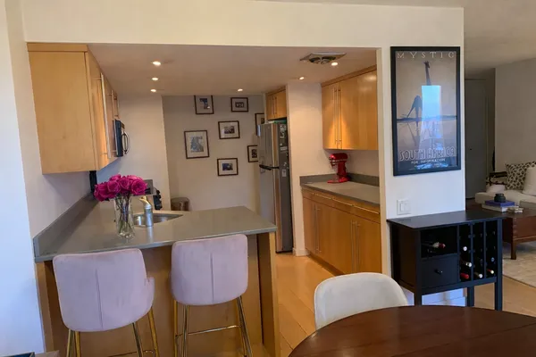 a kitchen with stainless steel appliances kitchen island granite countertop a dining table chairs and a refrigerator