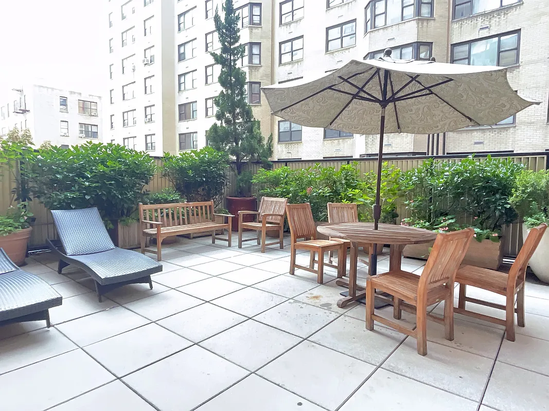400 East 90th Street, Unit 15B Manhattan, NY 10128 - Photo 13 of 15 a view of a patio with a table and chairs under an umbrella