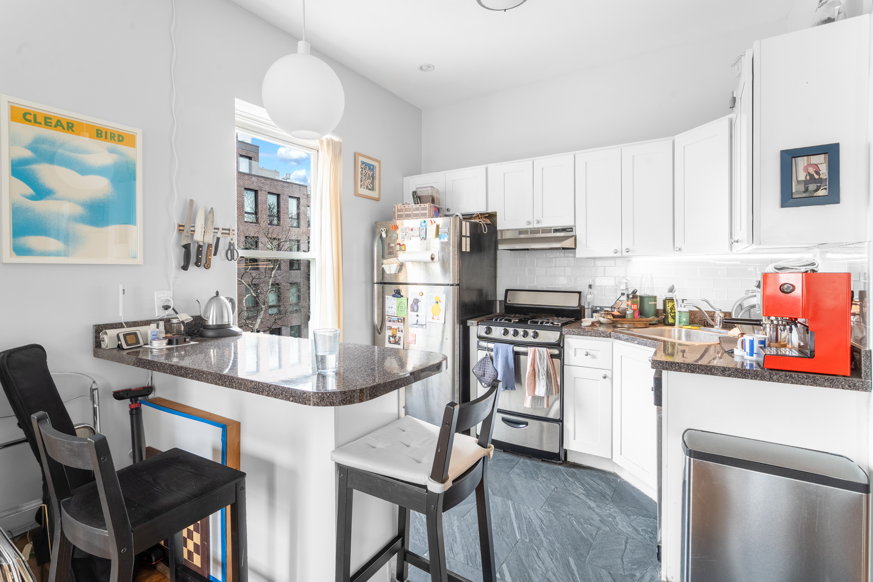 258 Halsey Street, Unit 3 Brooklyn, NY 11216 - Photo 5 of 10 a kitchen with stainless steel appliances granite countertop a stove a refrigerator a dining table and chairs