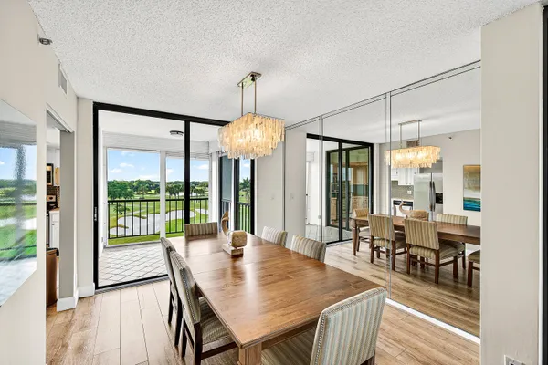a dining room with wooden floor a chandelier a wooden table and chairs