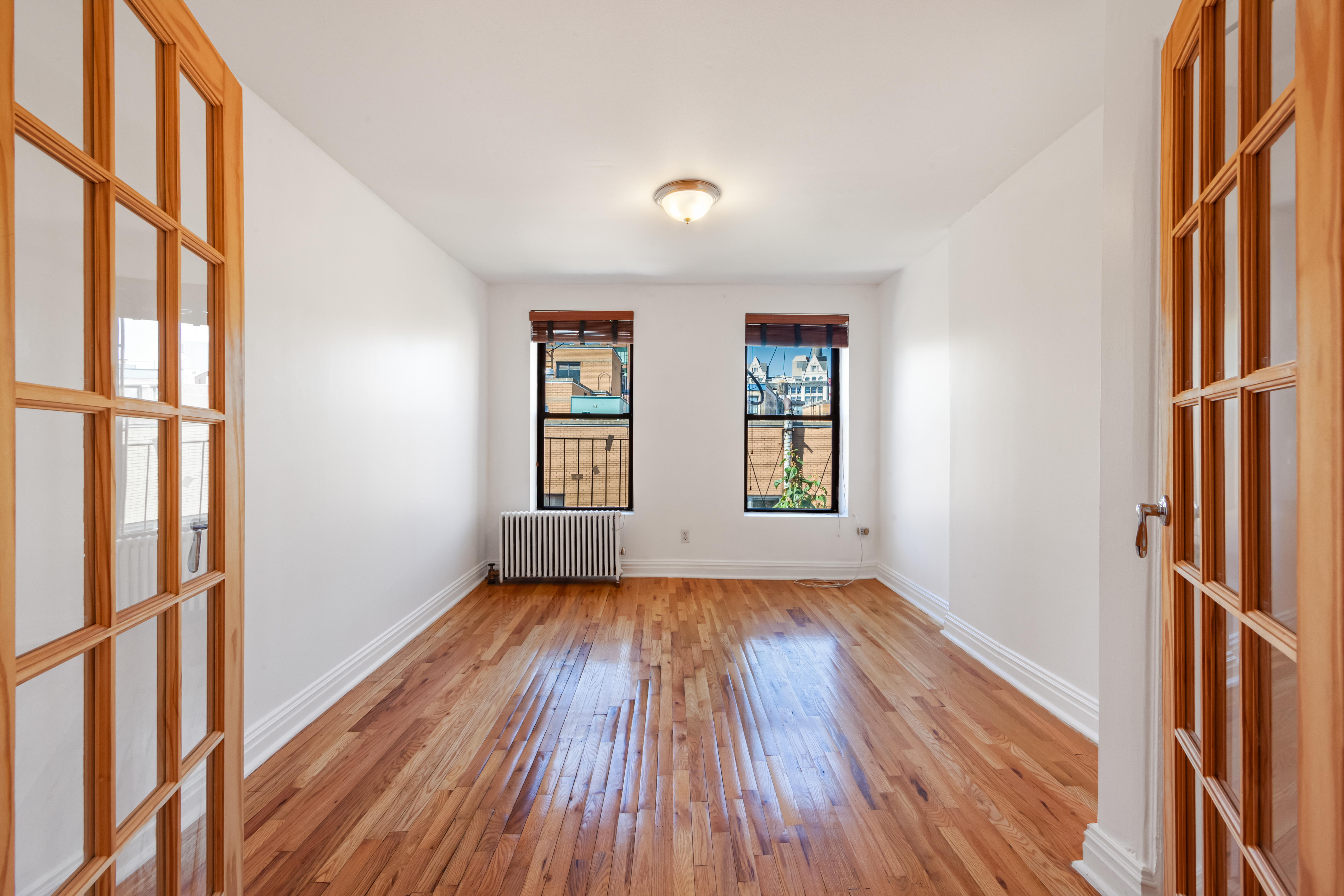 241 Mulberry Street, Unit 21 Manhattan, NY 10012 - Photo 1 of 5 an empty room with wooden floor and windows