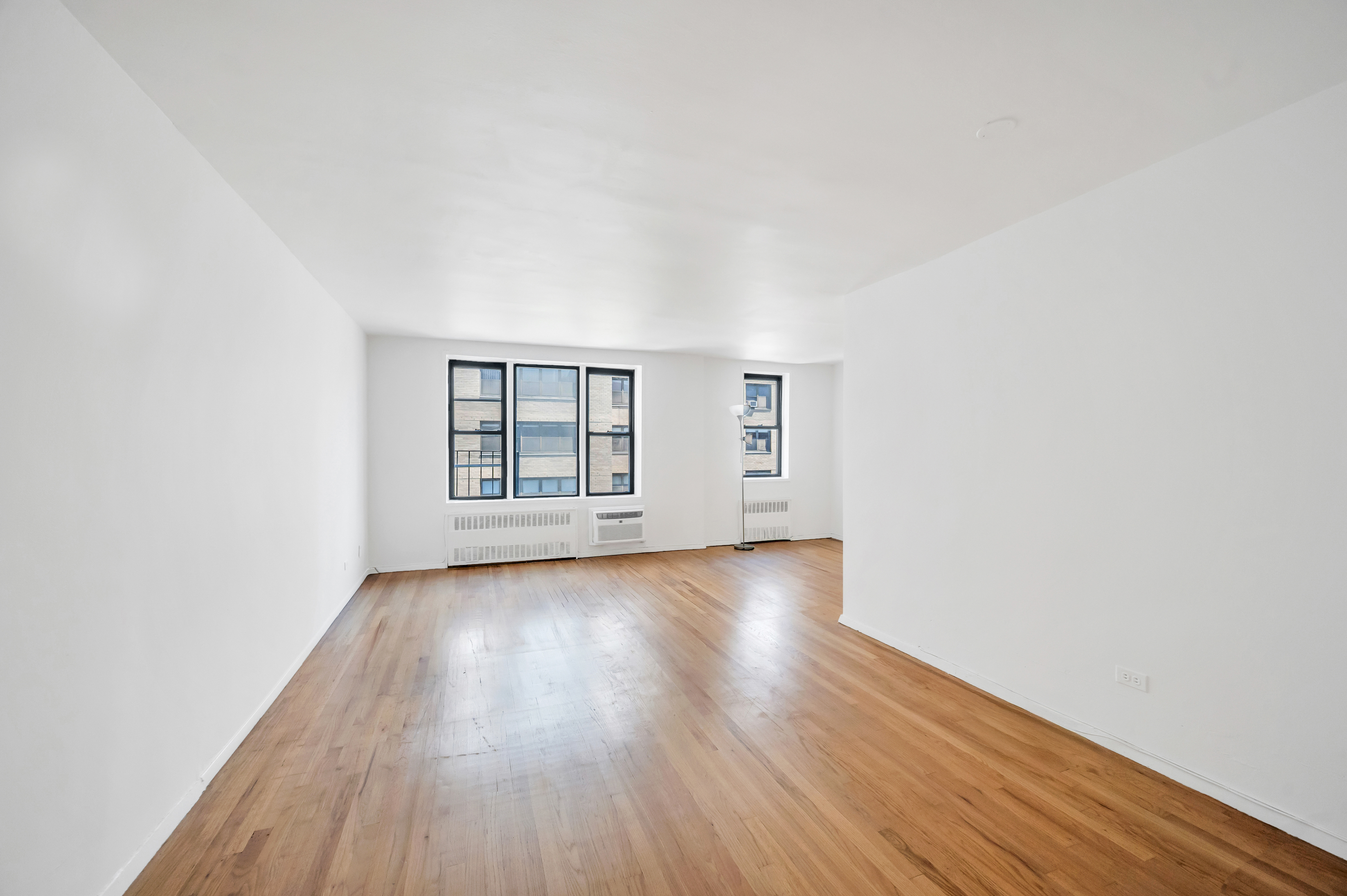 200 East 28th Street, Unit 6F Manhattan, NY 10016 - Photo 2 of 9 an empty room with wooden floor and windows