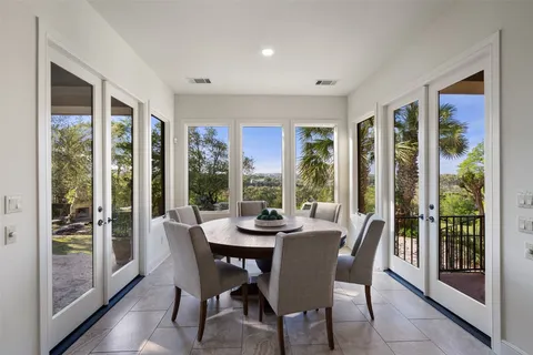 a dining room with furniture large windows and a potted plant