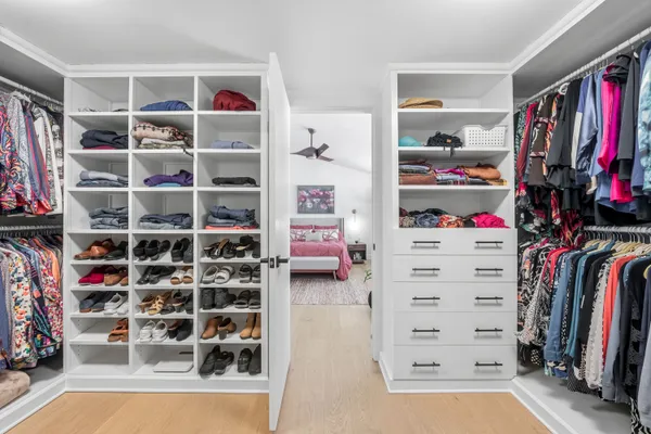 a view of walk in closet with clothes and shoes