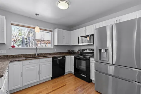 a kitchen with granite countertop stainless steel appliances a sink cabinets and a window
