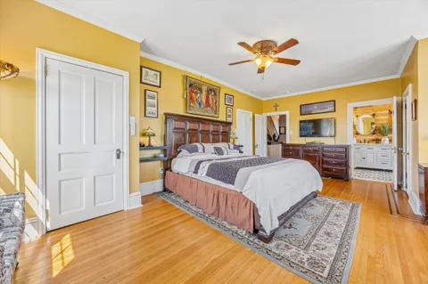 a spacious bedroom with a bed a dresser and a chandelier
