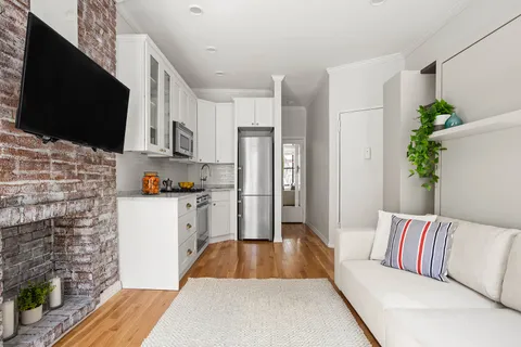a living room with stainless steel appliances furniture a flat screen tv and a fireplace