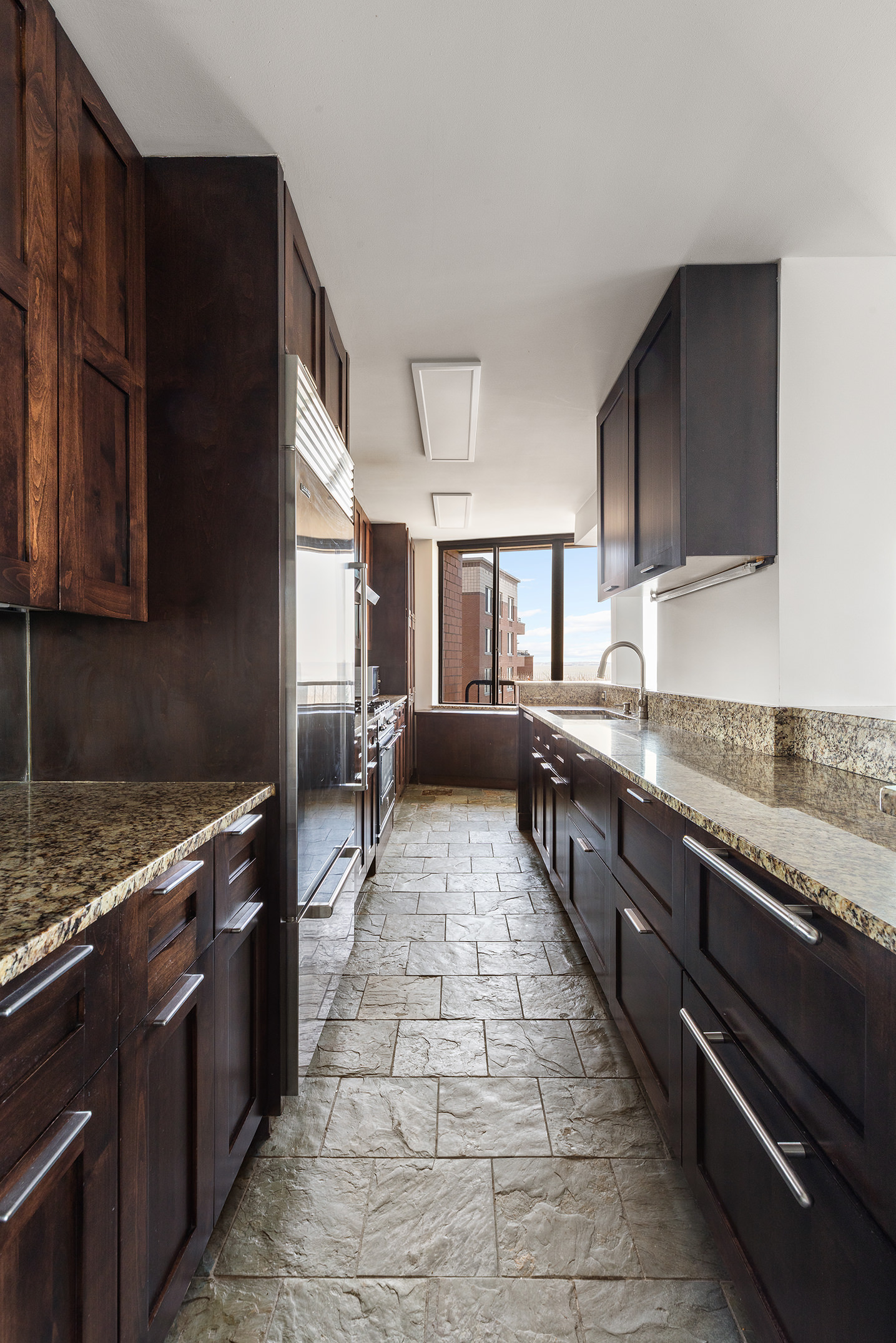 380 Rector Place, Unit 7LMN Manhattan, NY 10280 - Photo 4 of 14 a large kitchen with granite countertop a stove top oven a sink dishwasher and cabinets