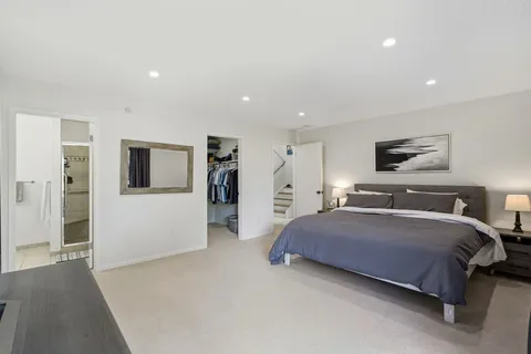 a spacious bedroom with a bed and a view of kitchen