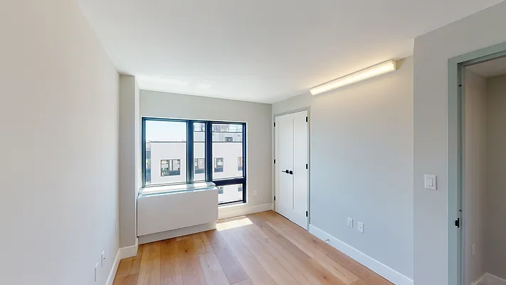 605 Hart Street, Unit 506 Brooklyn, NY 11221 - Photo 3 of 12 a view of an empty room with a window and wooden floor