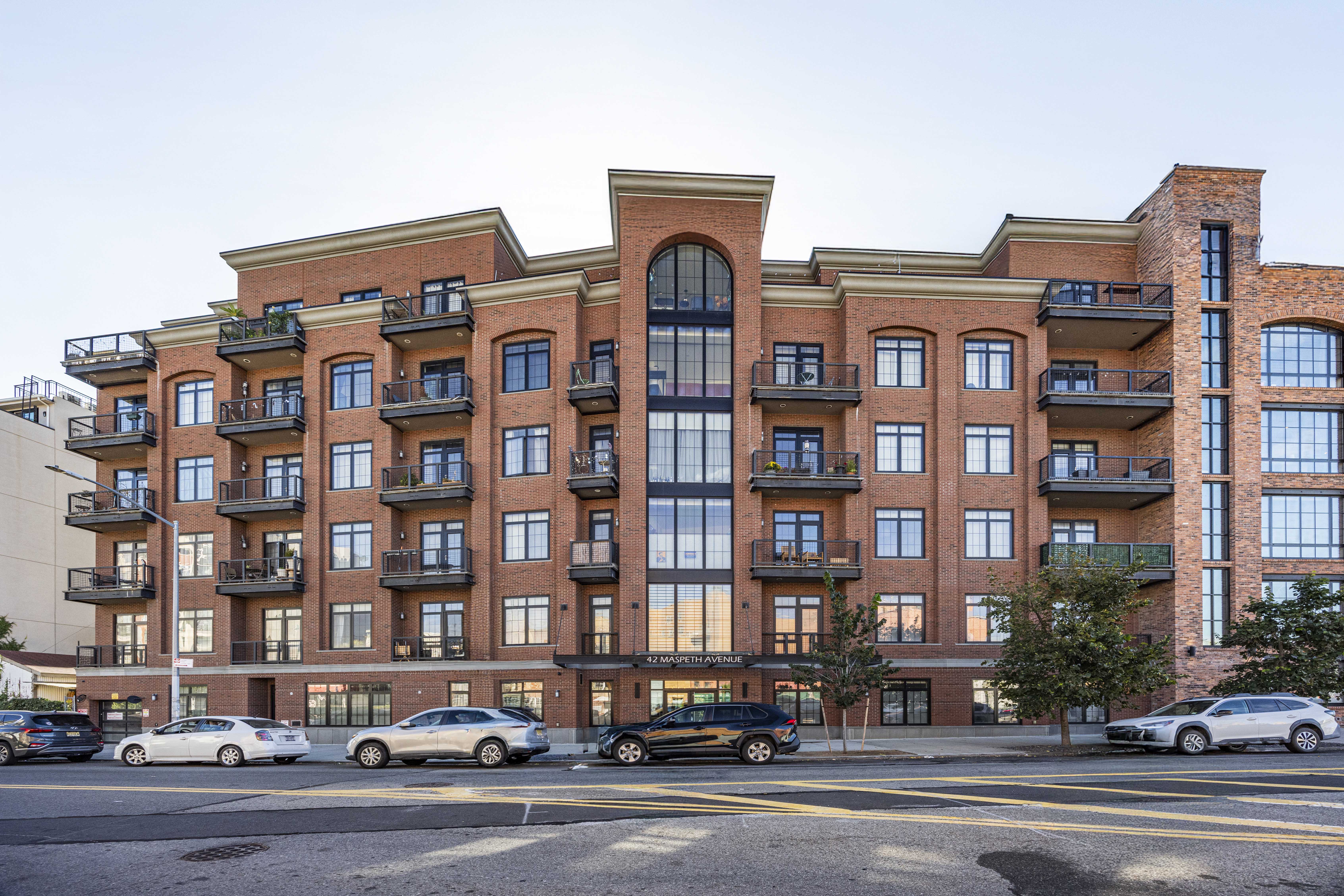 42 Maspeth Avenue, Unit 1D Brooklyn, NY 11211 - Photo 27 of 28 a front view of a building with lot of cars and trees
