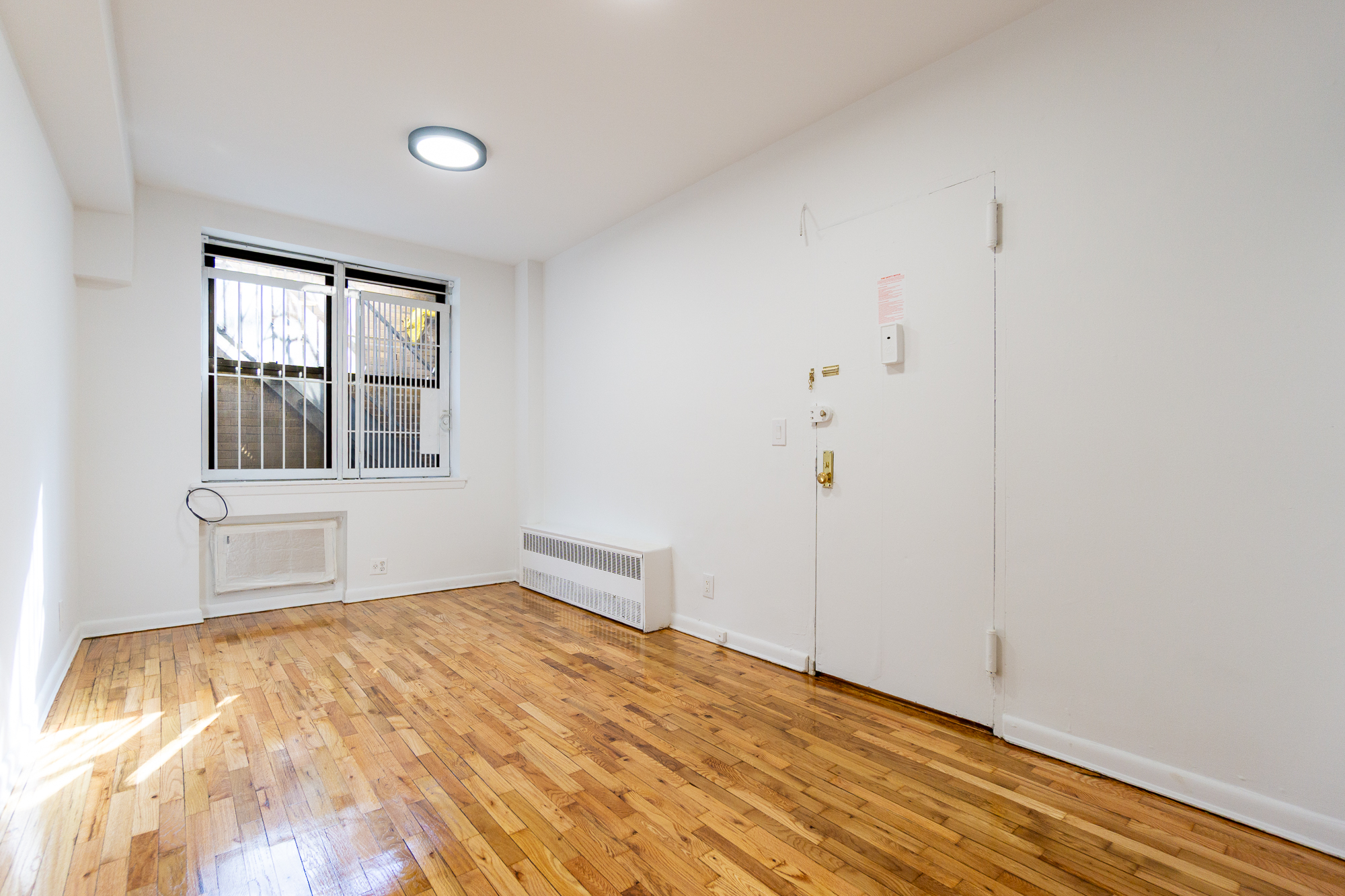 227 East 5th Street, Unit BE Manhattan, NY 10003 - Photo 1 of 7 a view of empty room with wooden floor and fan