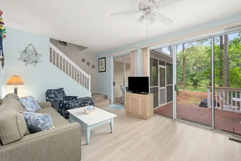 a living room with furniture a flat screen tv and a floor to ceiling window
