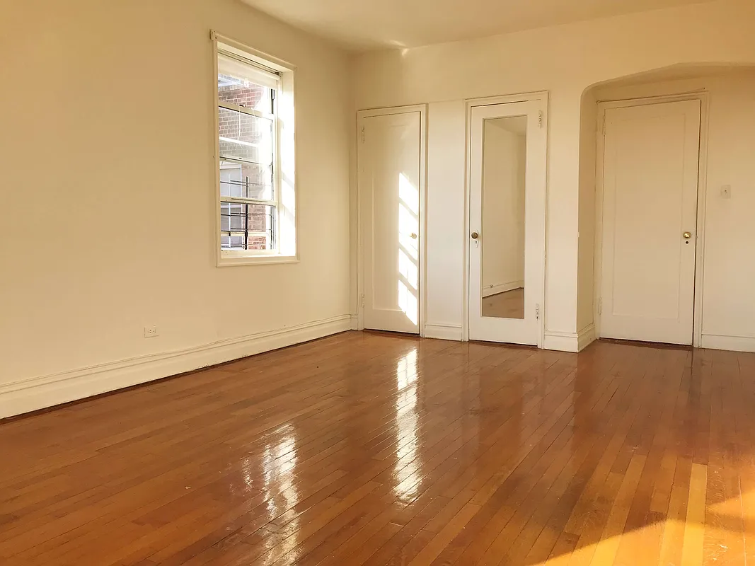100 Avenue P, Unit 6D Brooklyn, NY 11204 - Photo 2 of 4 an empty room with wooden floor and windows with curtains