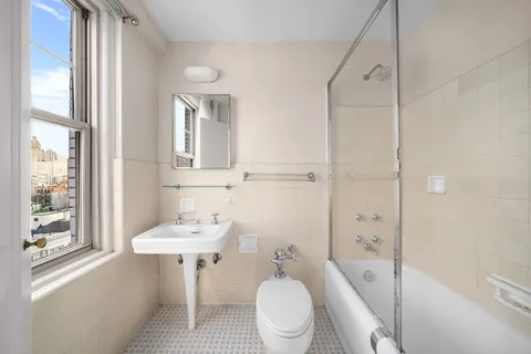 a bathroom with a sink a toilet a mirror and shower