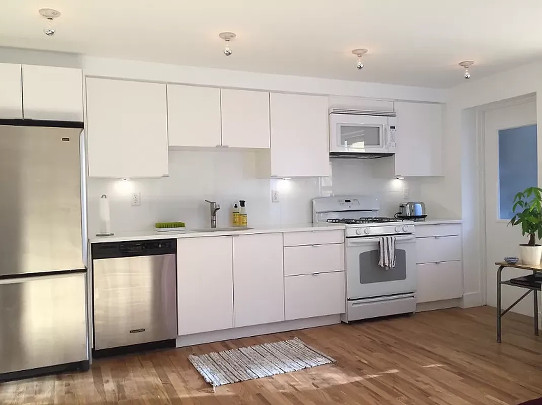 1370 Pacific Street, Unit 1 Brooklyn, NY 11216 - Photo 2 of 9 a kitchen with granite countertop white cabinets and white appliances