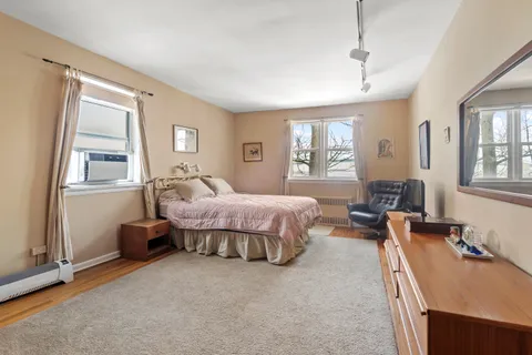 a spacious bedroom with a bed a table and windows