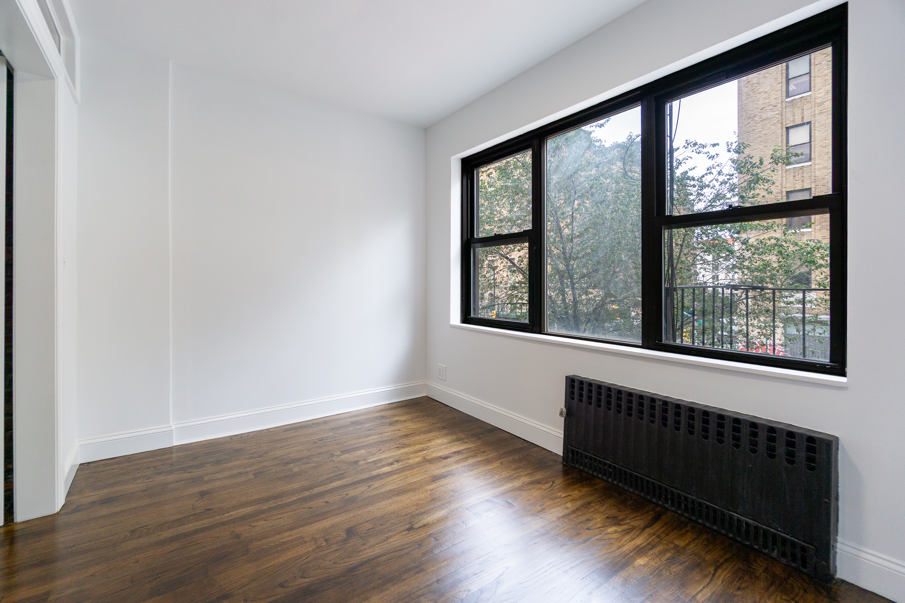 205 2nd Avenue, Unit 3B Manhattan, NY 10003 - Photo 4 of 9 a view of an empty room with wooden floor and a window