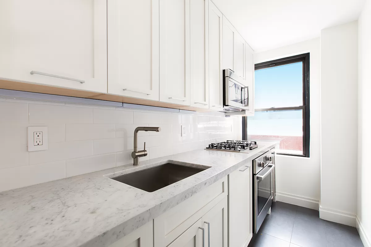 230 Riverside Drive, Unit 17D Manhattan, NY 10025 - Photo 8 of 18 a kitchen with stainless steel appliances granite countertop a sink stove and white cabinets