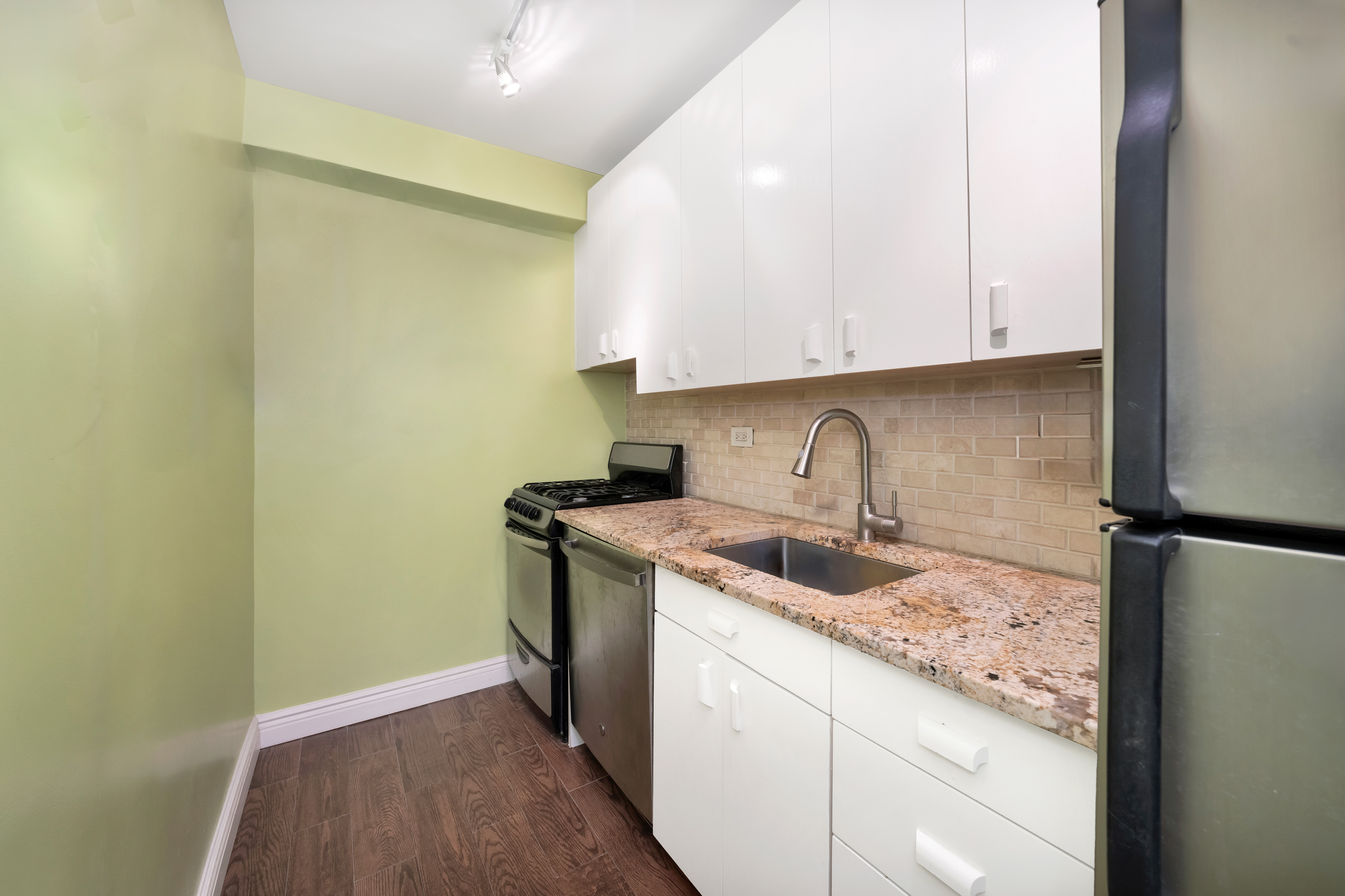 251 East 51st Street, Unit 5B Manhattan, NY 10022 - Photo 4 of 8 a kitchen with a sink a refrigerator and cabinets