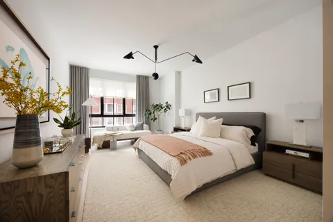 a bedroom with a bed couch and potted plant on the dresser