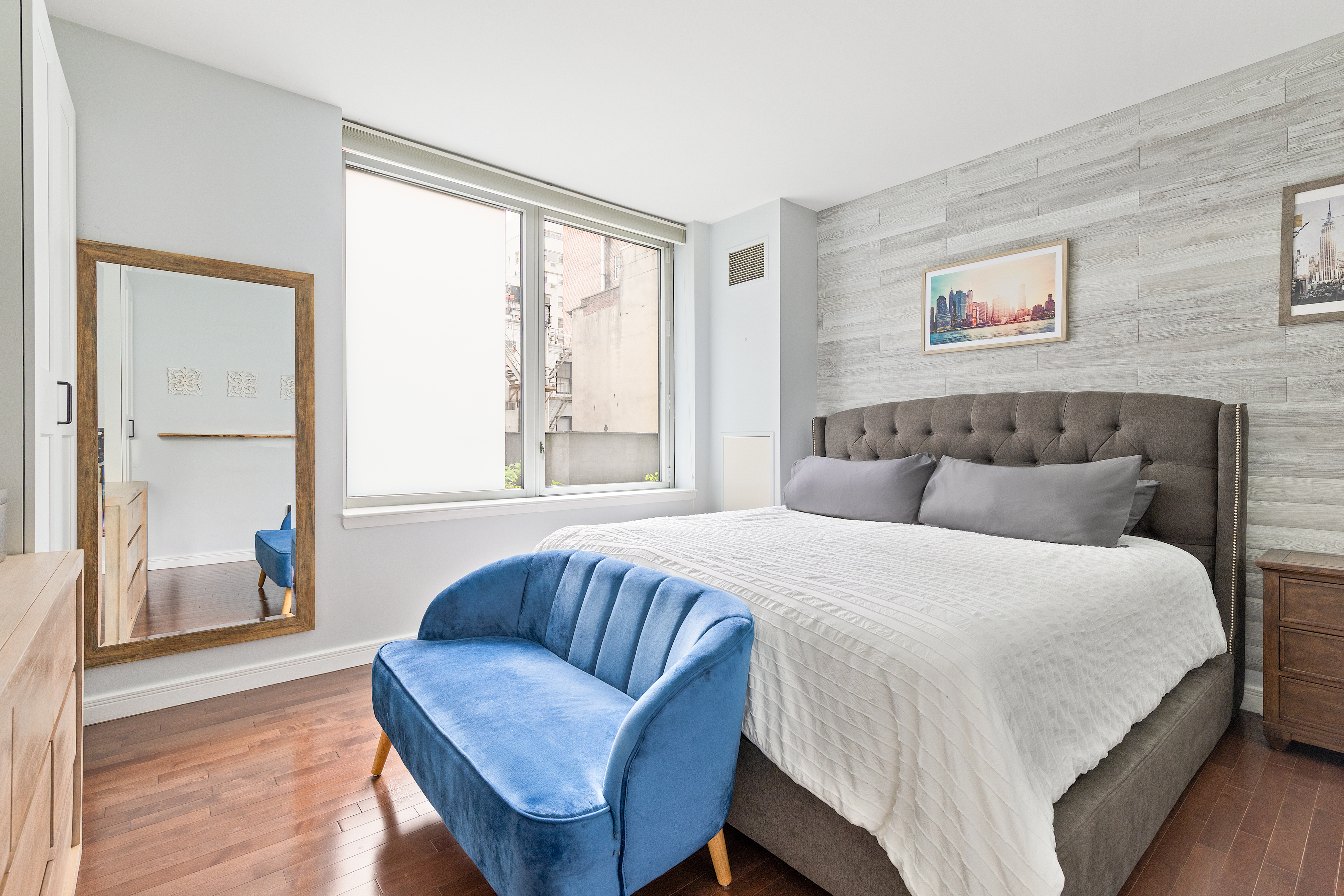 225 East 34th Street, Unit 3K Manhattan, NY 10016 - Photo 6 of 19 a bedroom with a bed and a couch with wooden floor