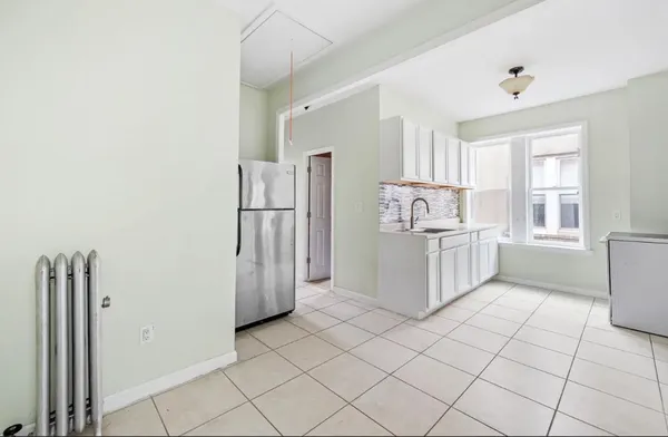 a kitchen with white cabinets and refrigerator