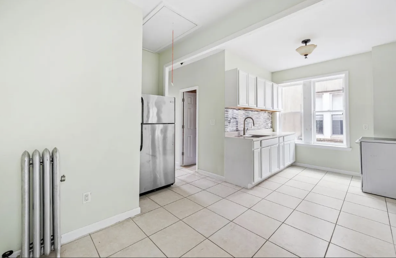 96 East 32nd Street, Unit 2 Brooklyn, NY 11226 - Photo 3 of 6 a kitchen with white cabinets and refrigerator