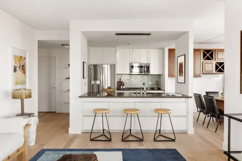 a kitchen with stainless steel appliances granite countertop a dining table chairs refrigerator and sink