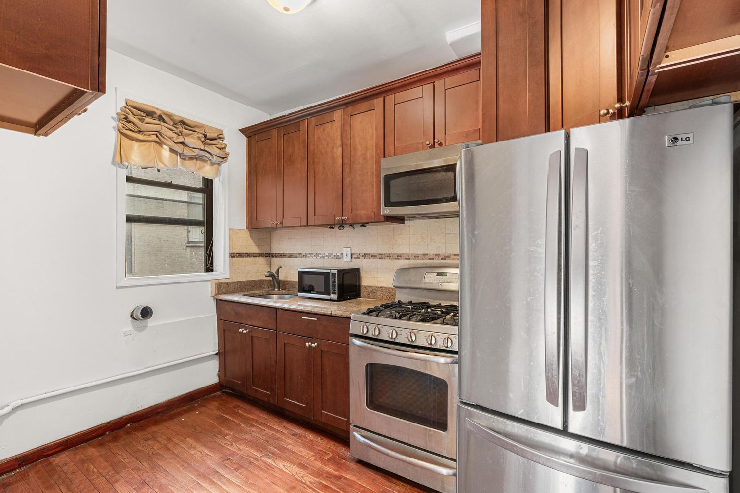 a kitchen with granite countertop a refrigerator stove and microwave