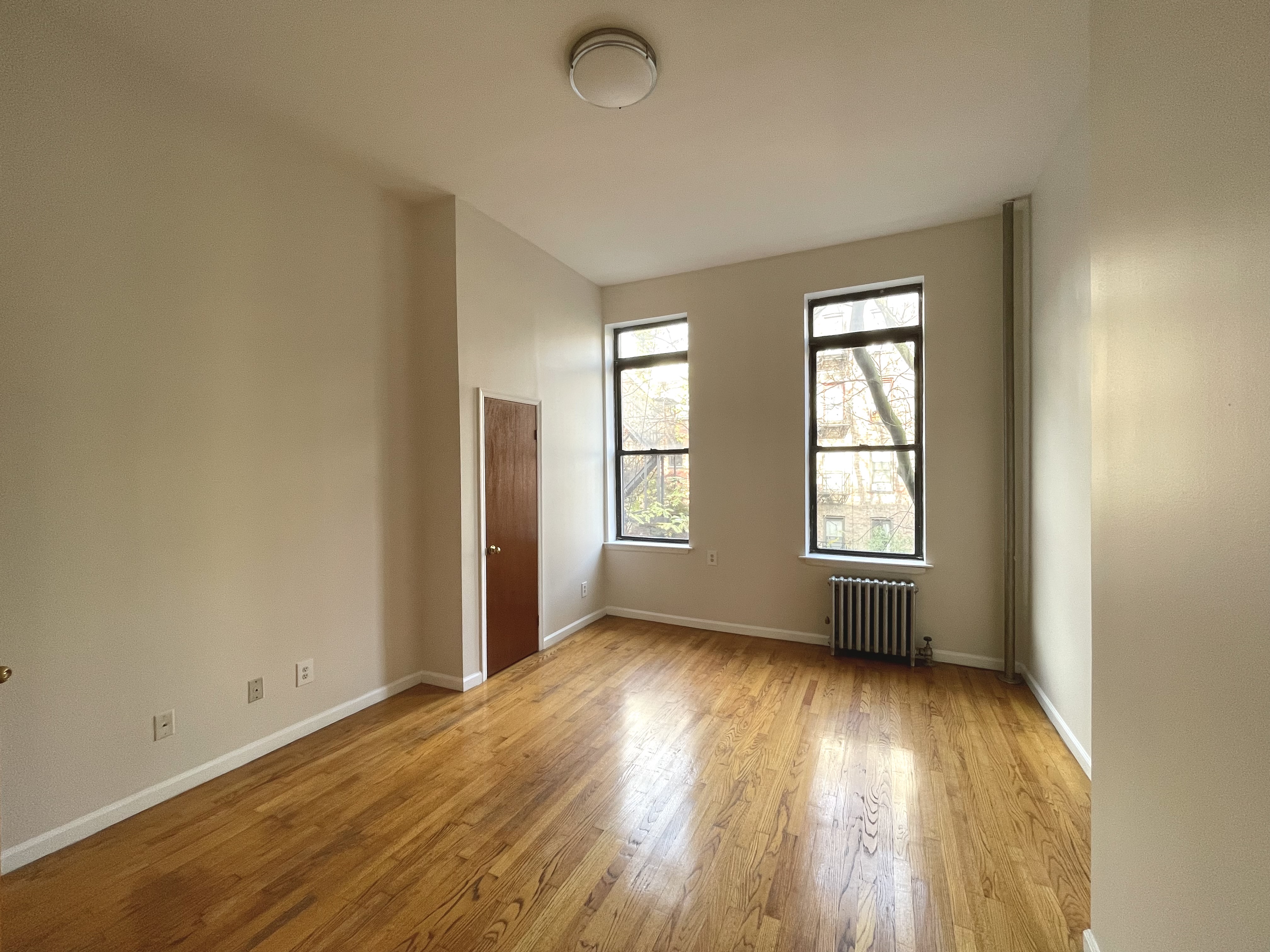 95 St Marks Place, Unit 6 Manhattan, NY 10009 - Photo 8 of 14 an empty room with wooden floor and windows