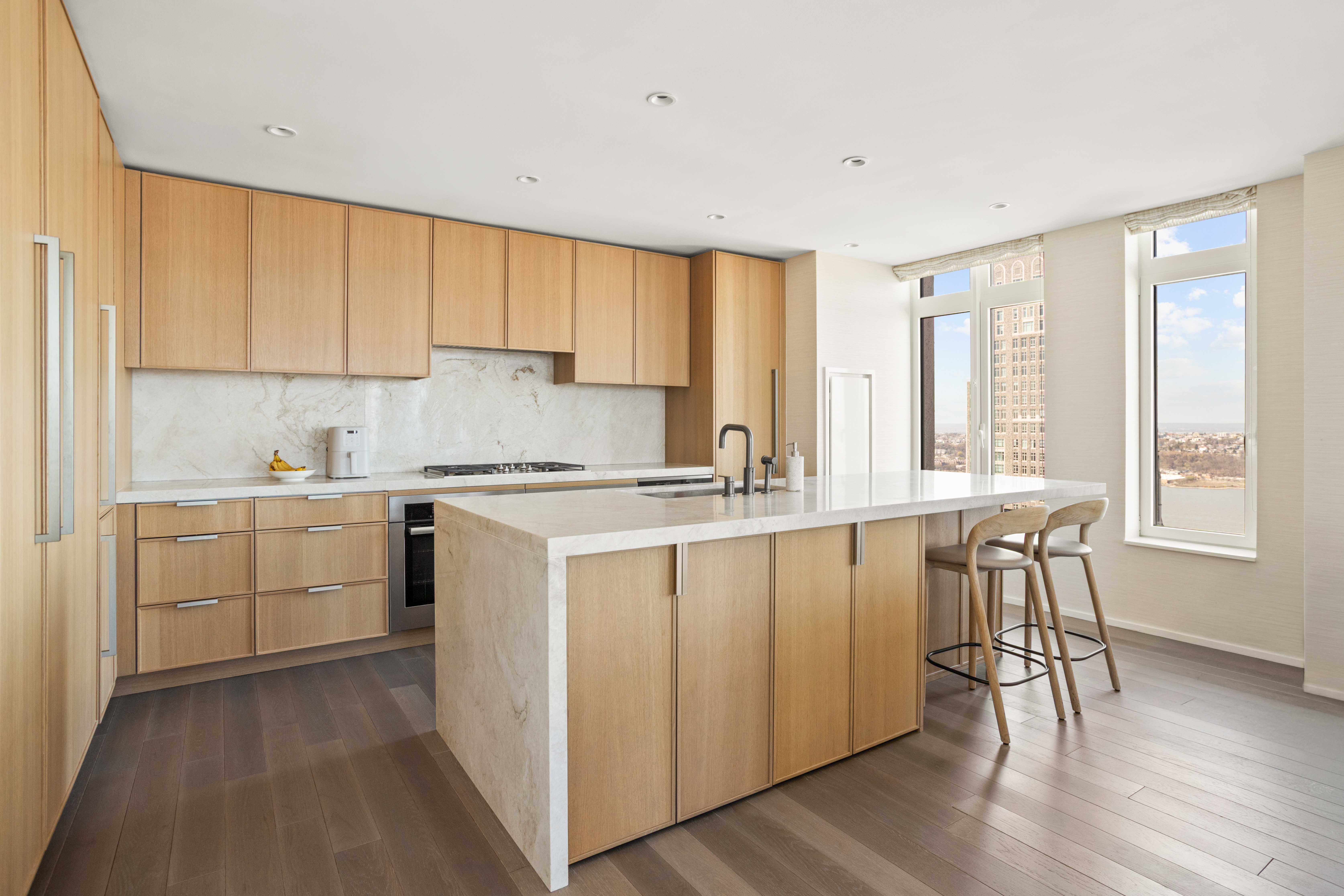 543 West 122nd Street, Unit PH31A Manhattan, NY 10027 - Photo 11 of 40 a kitchen with a stove a sink and white cabinets with wooden floor next to windows