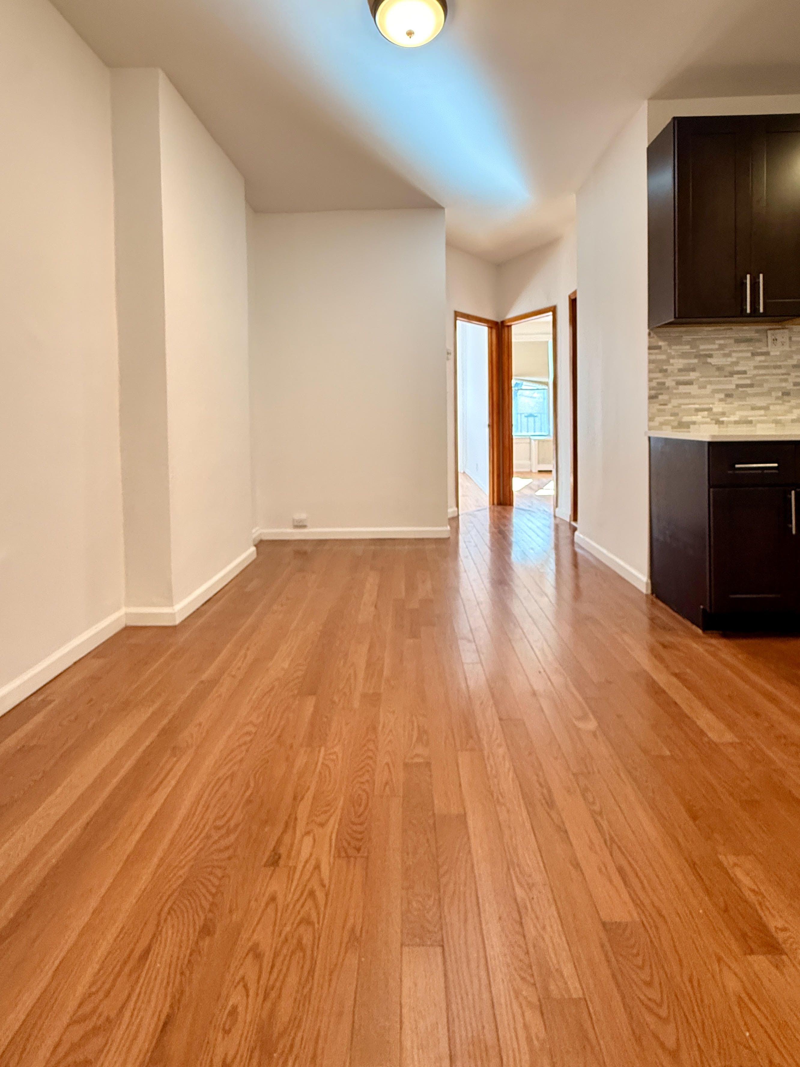 a view of an empty room with glass door and wooden floor