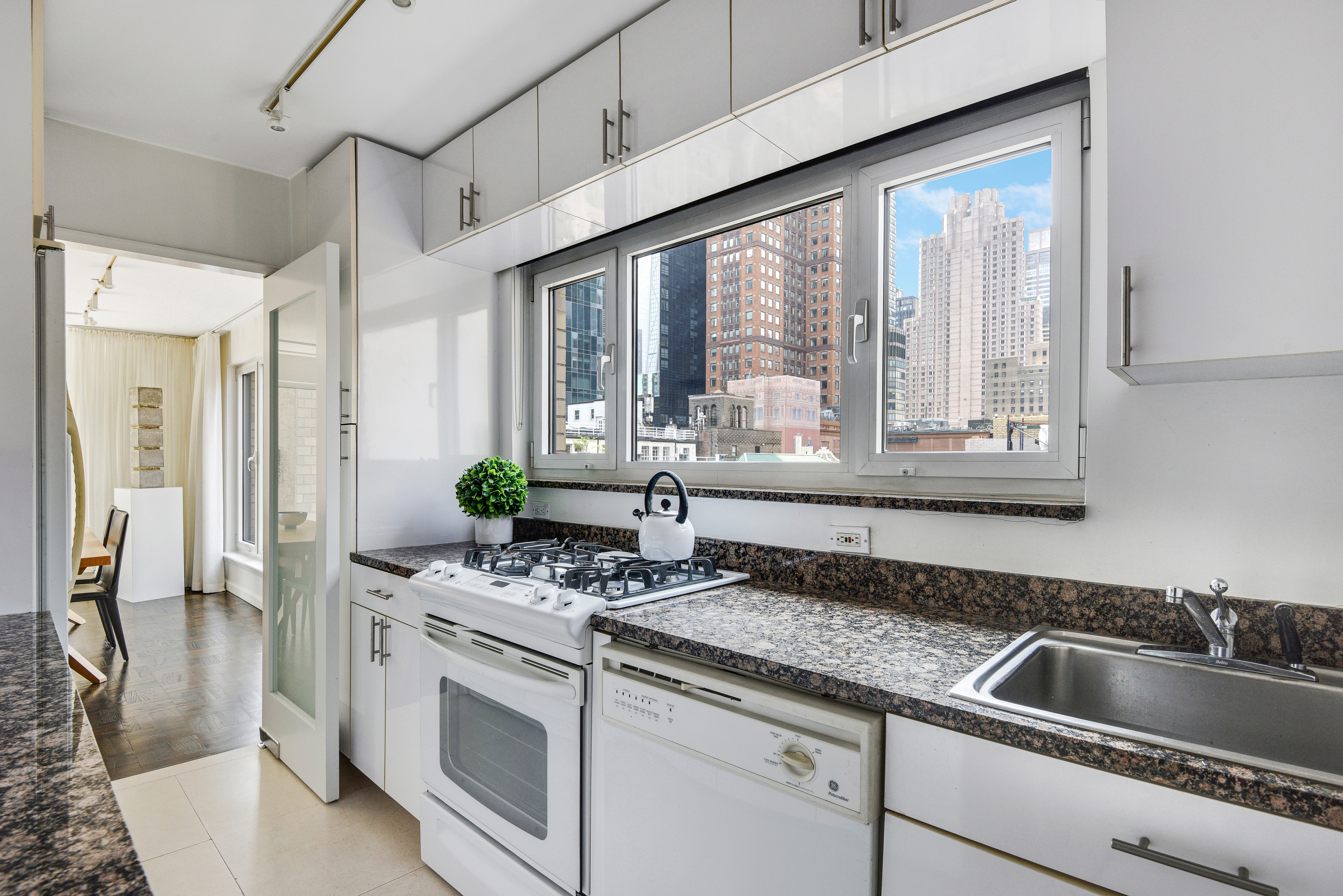 200 Central Park South, Unit 19J Manhattan, NY 10019 - Photo 9 of 12 a kitchen with stainless steel appliances granite countertop a sink and a white cabinets