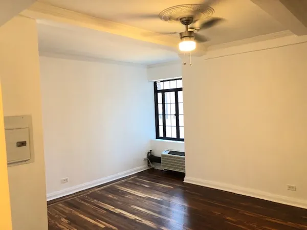 an empty room with wooden floor fan and windows
