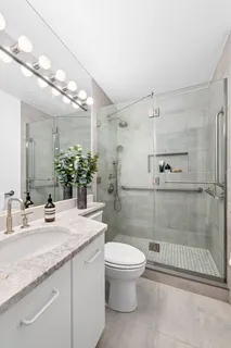 a bathroom with a granite countertop sink toilet a mirror and shower