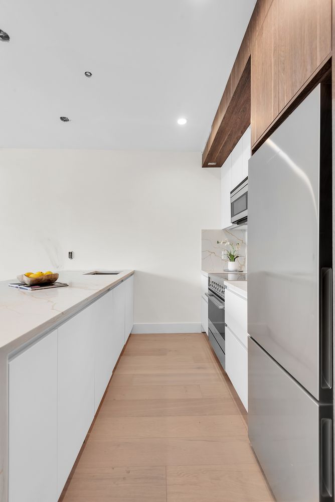 156 Somers Street, Unit 3B Brooklyn, NY 11233 - Photo 6 of 8 a kitchen with a refrigerator and white cabinets