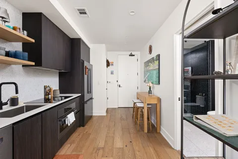 a kitchen with stainless steel appliances granite countertop a refrigerator a sink dishwasher a stove and white countertops with wooden floor