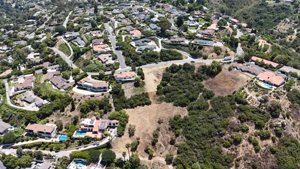 an aerial view of residential houses with outdoor space and trees