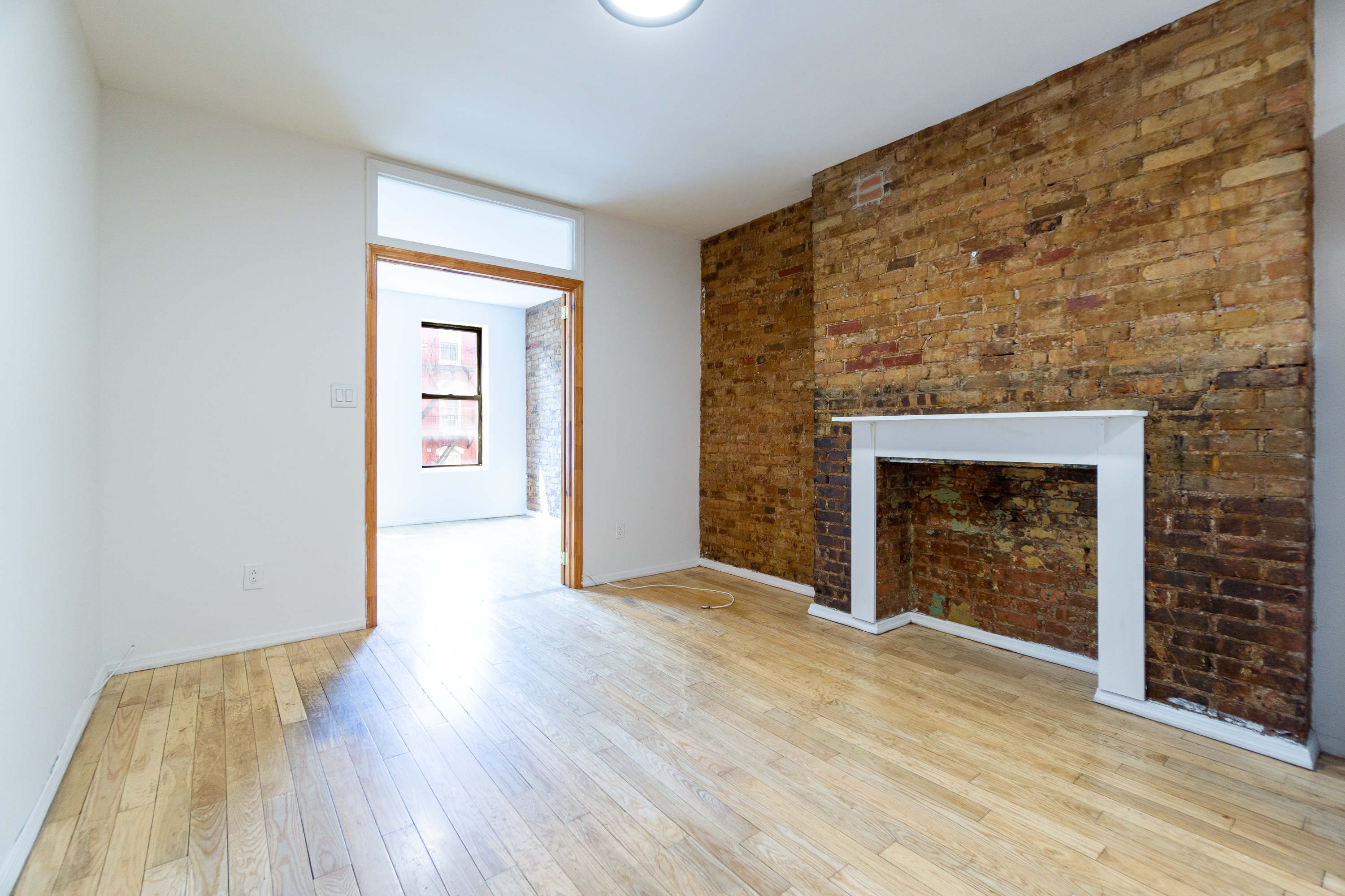 339 East 6th Street, Unit 12 Manhattan, NY 10003 - Photo 3 of 12 an empty room with wooden floor a fireplace and windows